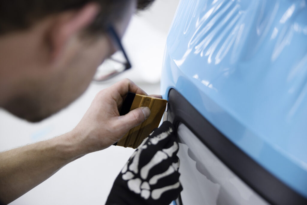 Шумоизолация - видове и съвети 4 close up man wrapping car with blue cover