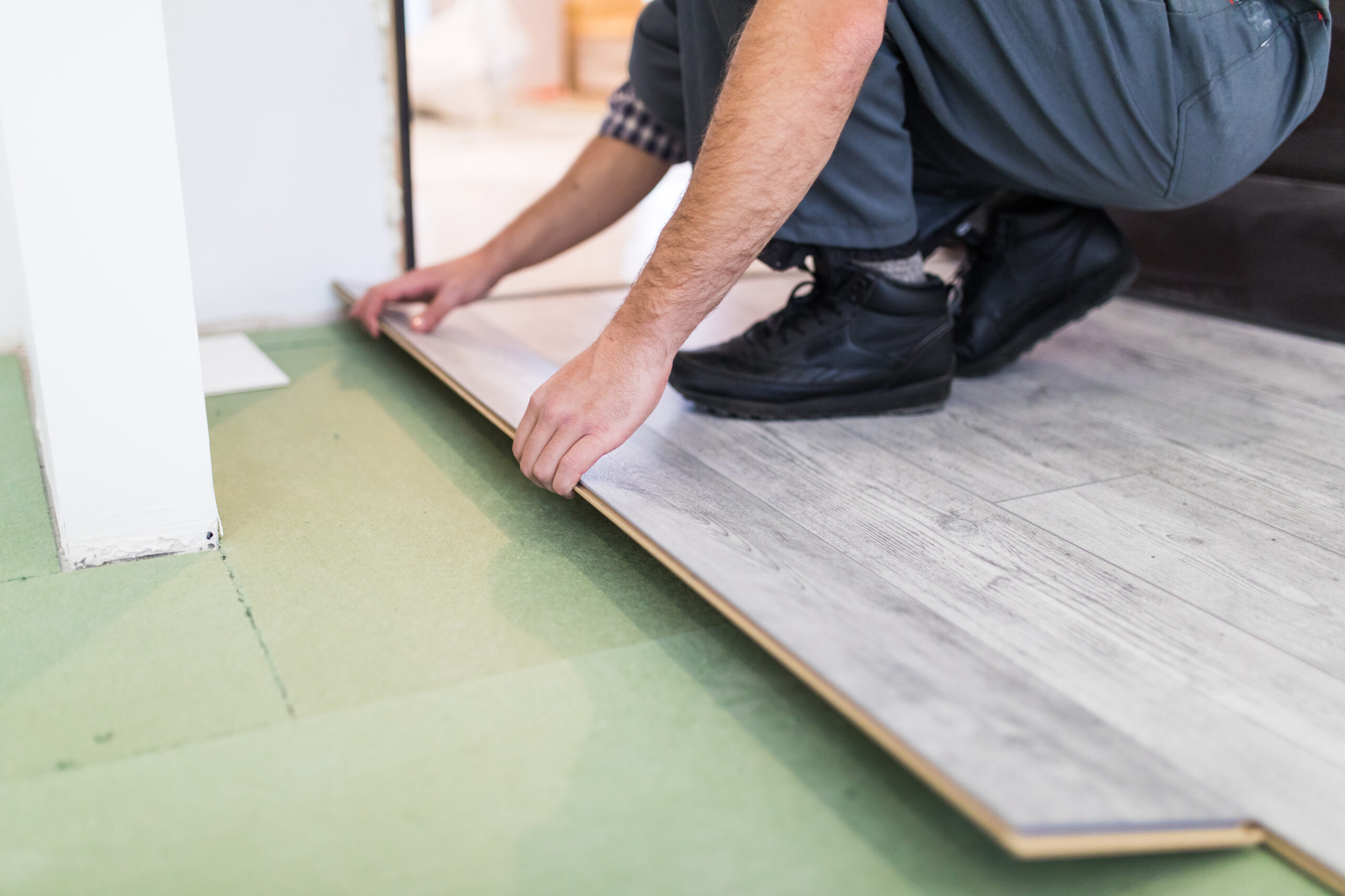 Полагане на ламинат: Инструменти и често допускани грешки 1 worker processing floor with laminated flooring boards scaled