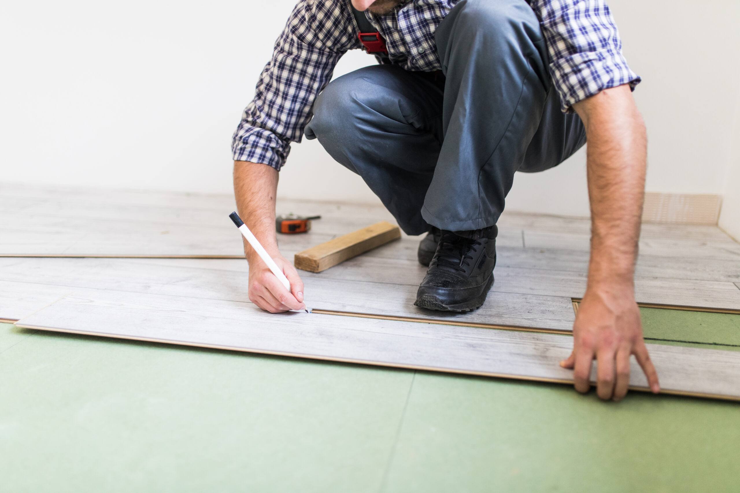 Полагане на ламинат: Инструменти и често допускани грешки 7 young worker lining floor with laminated flooring boards scaled